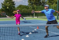 Adolescente ragazza in allenamento di tennis sul campo con istruttore maschio . — Foto stock