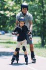 Nonno insegnamento nipote pattinaggio a rotelle nel parco estivo . — Foto stock