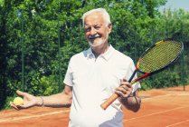 Старший теннисист, позирующий с мячом и ракеткой . — стоковое фото