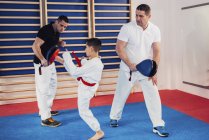 Des instructeurs de taekwondo entraînent un petit garçon en classe . — Photo de stock