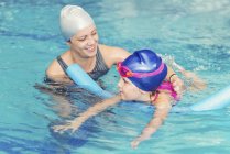 Menina aprendendo a nadar com instrutor na piscina pública . — Fotografia de Stock