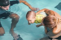 Mère avec bébé garçon et instructeur de natation masculin dans la piscine . — Photo de stock