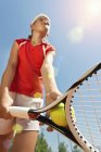 Vue à angle bas d'une joueuse de tennis adolescente servant en contre-jour . — Photo de stock