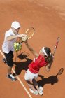 Jugador de tenis adolescente en entrenamiento con entrenador practicando servicio . - foto de stock