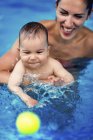 Madre jugando con el niño en la piscina
. - foto de stock