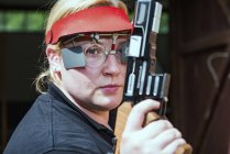 Mittlere erwachsene Frau bereitet sich auf Sportpistolenschießen vor. — Stockfoto