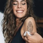 Mujer sonriente joven con nuevo tatuaje temporal en el brazo en el salón . - foto de stock