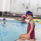 Kleines Mädchen blickt in Kamera neben öffentlichem Schwimmbad. — Stockfoto
