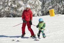 Menino pré-escolar esquiando com instrutor masculino . — Fotografia de Stock