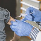 Médico haciendo la vacunación con jeringa al niño en edad preescolar en la clínica médica . - foto de stock