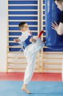Criança chutando saco de perfuração na classe taekwondo . — Fotografia de Stock