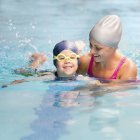 Bambino che impara a nuotare con istruttrice femminile in piscina . — Foto stock