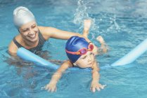 Девочка учится плавать с инструктором в общественном бассейне . — стоковое фото
