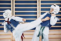 Dos niños de edad elemental ahorrando en clase taekwondo . - foto de stock