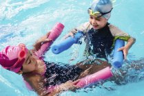 Crianças alegres brincando com macarrão de água na piscina
. — Fotografia de Stock