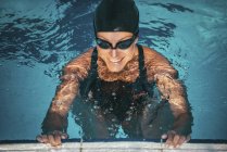 Nadador segurando na borda da piscina na água e sorrindo . — Fotografia de Stock