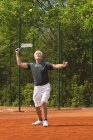 Jugador senior activo practicando tenis en la cancha . - foto de stock