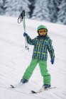 Маленький хлопчик в зимовому одязі лижі на снігових горах. — стокове фото
