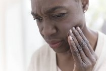 Зрелая женщина с зубной болью трогает лицо . — стоковое фото