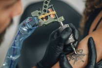 Master tattooing female skin in detail, toned image. — Stock Photo