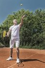 Jogador de tênis sênior que serve bola no campo . — Fotografia de Stock