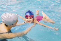 Menina aprendendo a nadar com instrutor na piscina pública . — Fotografia de Stock