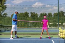 Teenie-Mädchen im Tennistraining mit Widerstandsband mit Trainer. — Stockfoto