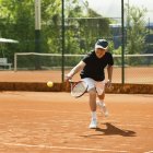 Aktiver Seniorenspieler übt Tennis auf dem Platz. — Stockfoto