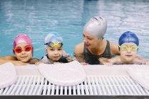 Niedliche Kinder, die Unterricht mit dem Lehrer im Schwimmbad haben. — Stockfoto