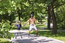 Мальчик катается на роликах в парке с дедушкой . — стоковое фото