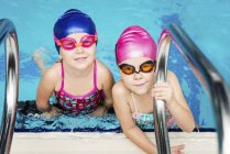 Little girls looking in camera in water of swimming pool. — Stock Photo