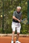 Aktiver Seniorenspieler übt Tennis auf dem Platz. — Stockfoto