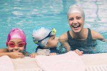 Allegro istruttore di nuoto che si diverte con i bambini durante la lezione in piscina . — Foto stock