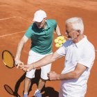 Senior Mann hat Tennisstunde mit männlichem Trainer. — Stockfoto