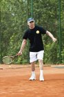 Active senior man playing tennis on court. — Stock Photo