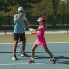 Männlicher Tennislehrer trainiert jugendliche Spielerin auf dem Platz. — Stockfoto
