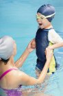 Cheerful little boy taking breath in swimming class in public pool. — Stock Photo