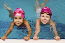 Little girls practicing in water of swimming pool. — Stock Photo