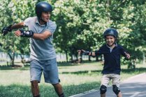 Rollerskating race with grandfather and grandson having fun in park. — Stock Photo