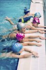 Groupe d'enfants en classe de natation avec instructeur pratiquant le coup de pied . — Photo de stock