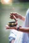 Close-up of female hands holding Tibetan singing bowl outdoors. — Stock Photo