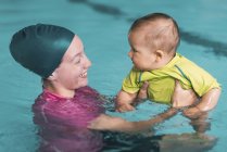 Istruttore femminile in possesso di bambino ragazzo con classe di nuoto — Foto stock