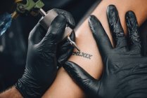 Mestre tatuando a pele feminina em detalhes no estúdio . — Fotografia de Stock