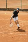 Старший игрок отбивает мяч на теннисном корте . — стоковое фото