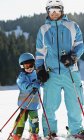 Niño de edad elemental que tiene clase de esquí con padre . - foto de stock