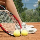 Feet of female tennis player on break with tennis shoes, racket and balls. — Stock Photo