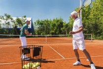 Aktive Senioren üben in Tennisklasse mit Trainer. — Stockfoto