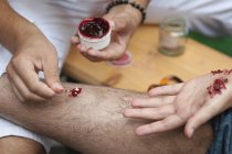 Special effects makeup artist creating realistic leg and hand injuries. — Stock Photo