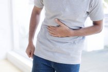 Mid section of man touching stomach in pain. — Stock Photo