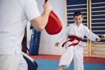 Instructeur de taekwondo formant petit garçon en classe . — Photo de stock